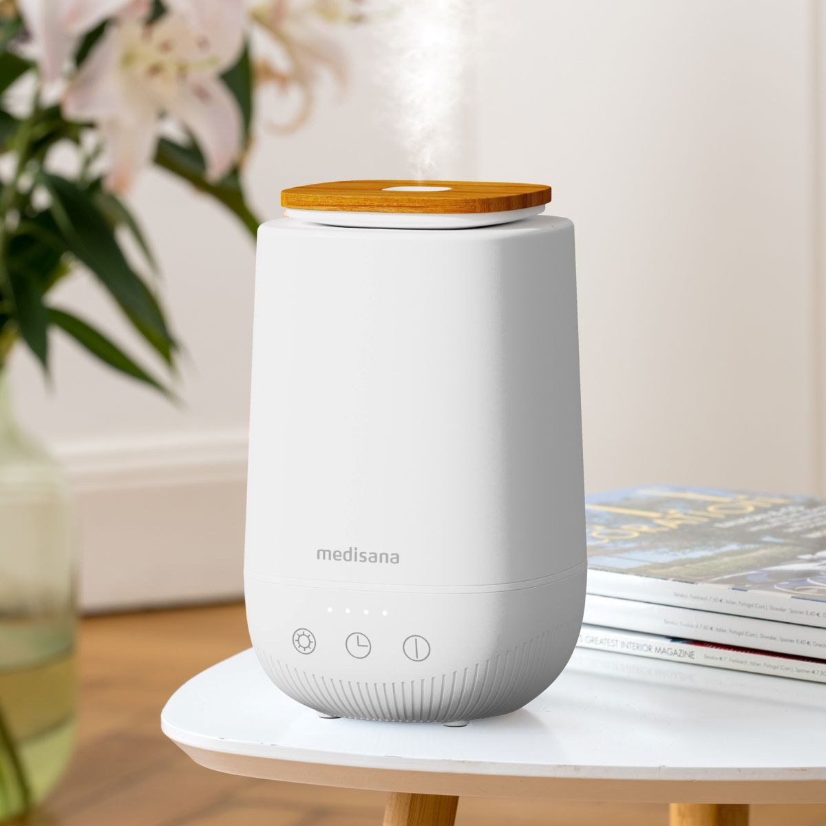 Ein weißer Aroma-Diffuser mit Holzdeckel steht auf einem Beistelltisch und gibt feinen Duftnebel ab.